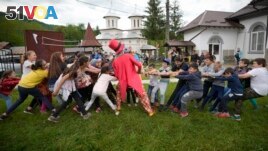 Children play during an eyesight examination performed by volunteer ophthalmologists, in Nucsoara, Romania, Saturday, May 29, 2021.