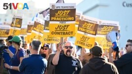 FILE - UPS workers hold placards at a rally held by the Teamsters Union on July 19, 2023 in Los Angeles, California, ahead of an August 1st deadline for an agreement on a labor contract deal. (Photo by Frederic J. BROWN / AFP)