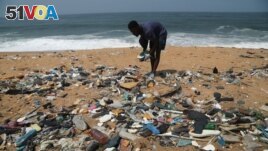 Ivorian painter Aristide Kouame 26, who paints optical effects artworks with worn soles, picks up used flip-flops among the garbage on a beach in Abidjan, Ivory Coast August 2, 2021. (REUTERS/Luc Gnago)
