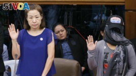 Choi Kyung-jin, left, the widow of South Korean businessman Jee Ick-joo take their oaths at the start of the Philippine Senate probe of the killing.