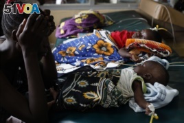 An unidetified mother as watches over her child who is suffering from severe malaria, as other children lay nearby, in the Siaya hospital in Western Kenya. Photo taken on Oct. 30, 2009.