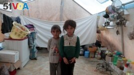 FILE - Syrian siblings, displaced from eastern Idlib province, pose for a picture in a tent at Atmeh camp in Syria, near the Turkish border, June 19, 2020.