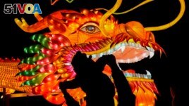 A man holds a child in front of a giant dragon lantern decoration near the popular Houhai Lake in Beijing, China on February 8, 2024. (AP Photo/Andy Wong)