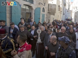 Christian clergymen carry a wooden relic believed to be from Jesus' manger outside the Church of the Nativity, traditionally believed by Christians to be the birthplace of Jesus Christ, in the West Bank city of Bethlehem, Saturday, Nov. 30, 2019.