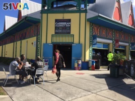 Customers sit outside the Caribbean Marketplace in Little Haiti, Miami, Florida. (Photo: S. Lemaire / VOA)