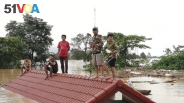 Villagers take refuge on a rooftop above flood waters from a collapsed dam in the Attapeu district of southeastern Laos, July 24, 2018.
