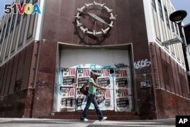 A woman walks in front of a closed bank in the neighborhood of Rio Piedras in San Juan, Puerto Rico, June 29, 2015. 