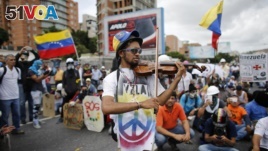Wuilly Arteaga plays his violin prior clashes with government forces at a march against the government of President Nicolas Maduro in Caracas, Venezuela.