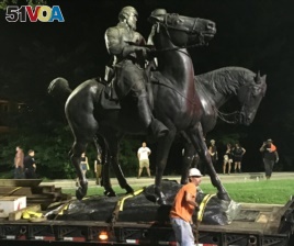 Workers remove the monuments to Robert E. Lee, commander of the pro-slavery Confederate army in the American Civil War, and Thomas 