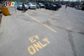 Four electric vehicle charging spots stand empty in a grocery story parking lot in Lawrence, Kan., Monday, April 5, 2021.