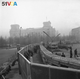 This Nov. 20, 1961 photo shows 12 feet high boards hiding the work as East German troops erect a new concrete wall at the Brandenburg Gate, marking the East-West border in Berlin. In background is the former Reichstag building which is in West Berlin. (AP Photo)