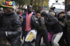 Migrants run to board buses to temporary shelters in Paris, Friday, Nov. 4, 2016.