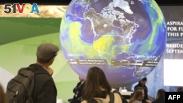 People look at an Earth globe display at the COP21, the United Nations conference on climate change in Le Bourget, Dec. 10, 2015.