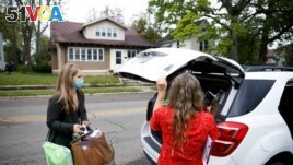Rocking Horse Community Outreach Worker Amanda Ambrosio (left) and Hadley Smiddy (right) deliver food to a patient in the Purple Apron Program, which provides food, nutrition classes, and a supportive community for patients, in Springfield, Ohio, U.S., May 17, 2021. (REUTERS)