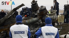 OSCE members watch as recovery workers in rebel-controlled eastern Ukraine load debris from the crash site of Malaysia Airlines Flight 17, in Hrabove, Ukraine, Nov. 16, 2014.