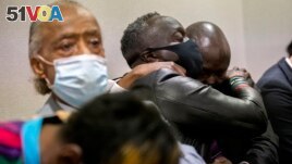 Ahmaud Arbery's father Marcus Arbery, center, his hugged by his attorney Benjamin Crump after the jury convicted Travis McMichael in the Glynn County Courthouse, Nov. 24, 2021, in Brunswick, Ga. (AP Photo/Stephen B. Morton, Pool)