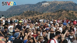 A crowd gathers in front of the Hollywood sign at the Griffith Observatory to watch the solar eclipse in Los Angeles on Monday, Aug. 21, 2017. (AP Photo/Richard Vogel)