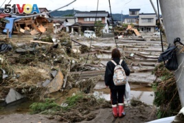 A woman looks at flood-damaged homes in Nagano on October 15, 2019, after Typhoon Hagibis hit Japan on October 12 unleashing high winds, torrential rain and triggered landslides and catastrophic flooding.