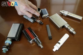 In this Tuesday, April 10, 2018 photo Marshfield High School Principal Robert Keuther displays vaping devices that were confiscated from students in such places as restrooms or hallways at the school in Marshfield, Mass.