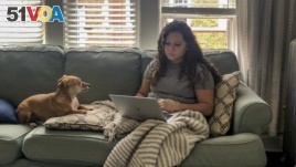 In this March 27, 2020 photo, Vicktery Zimmerman works from her home in Chicago during the order to shelter in place. A self-proclaimed extrovert, Zimmerman has come up with workarounds like video calls to deal with social distancing. (Justin Zimmerman via AP)