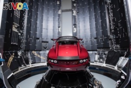 This Dec 6, 2017 photo made available by SpaceX shows a Tesla car next to the fairing of a Falcon Heavy rocket in Cape Canaveral, Fla. For the Heavy's inaugural flight, the rocket will carry up Elon Musk's roadster. In addition to SpaceX, Musk runs the el