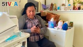 Rosalidia Dardon, 54, looks at a picture of her daughter in El Salvador as she sits in a refugee house in Texas, awaiting asylum or a protected immigration status on Nov. 4, 2021. (Acacia Coronado/Report for America via AP)