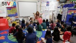 In this Thursday, May 23, 2013 photo, first grade teacher Lisa Cabrera-Terry, center, leads the class in a reading exercise at Jay W. Jeffers Elementary School, in Las Vegas. Eighty three percent of the incoming kindergartners at the school don't speak En