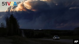 Smoke billows from the Fort McMurray wildfires as a truck drives down the highway in Kinosis, Alberta.