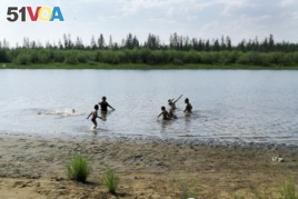 In this handout photo taken Sunday, June 21, 2020 and provided by Olga Burtseva, children play in the Krugloe lake outside Verkhoyansk, the Sakha Republic, about 4660 kilometers northeast of Moscow, Russia. (Olga Burtseva via AP)