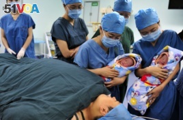 Nurses show a pair of fraternal twins to their mother (bottom) after they were born at the IVF centre of a hospital in Xi'an, Shaanxi province August 16, 2012.