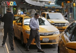 A taxi driver heads to his vehicle as other taxis line up outside LaGuardia Airport in New York.