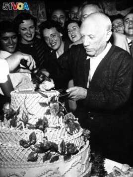 Pablo Picasso, famed Spanish painter, accepts first piece of 67-pound birthday cake as he celebrates his 75th birthday, with a birthday party at Vallauris in southern France on Oct. 24, 1956.