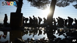 The sun rises as refugees and migrants walk to pass from the northern Greek village of Idomeni to southern Macedonia, Friday, Sept. 11, 2015. The sudden onset of autumn has taken tens of thousands by surprise all along the Balkans route from Greece to Hun
