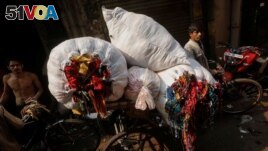 A man is transporting unused leftover fabric from factories at a market in New Delhi, India, November 4, 2021. The fabric will be repurposed to create high-end sustainable clothes. (REUTERS/Adnan Abidi)