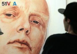 FILE - A man looks at a portrait of ex-spy Andrei Litvinenko by Russian artists Dmitry Vrubel and Viktoria Timofeyeva in the Marat Guelman gallery in Moscow.