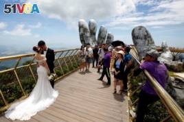 A couple stand near giant hands structure for their wedding photos on Gold Bridge on Ba Na hill near Danang city, Vietnam August 1, 2018. REUTERS/Kham