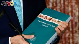 U.S. Secretary of State John Kerry holds a copy of the 2016 Trafficking in Persons (TIP) report for 2016.