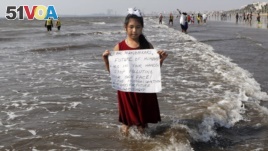 In this Friday, Feb 21, 2020, photo, environmental activist Licypriya Kangujam, 8, holds a sign at Juhu beach during a cleaning drive in Mumbai, India.