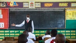 A teacher welcomes back students during a classroom lesson on day one of re-opening schools in Kampala, Uganda, Jan. 10, 2022.
