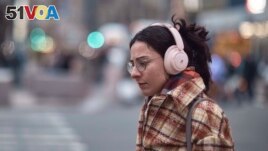 A woman walks using her headphones on Tuesday, Jan. 17, 2023, in New York. (AP Photo/Andres Kudacki)