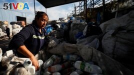 Paola Godoy, who works as a garbage recycler, handles empty bottles of milk in a sack filled with plastic meant to be recycled, in Lomas de Zamora, in the outskirts of Buenos Aires, Argentina July 8, 2022. (REUTERS/Agustin Marcarian)