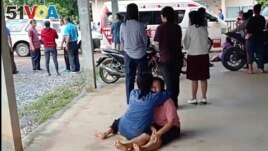 In this image taken from video, a woman is comforted outside the site of an attack at a childcare center, Thursday, Oct. 6, 2022, in the town of Nongbua Lamphu, north eastern Thailand. (Mungkorn Sriboonreung Rescue Group via AP)