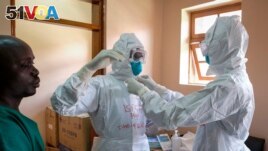 Doctors put on protective equipment as they prepare to visit a patient who was in contact with an Ebola victim, in the isolation section of Entebbe Regional Referral Hospital in Entebbe, Uganda Thursday, Oct. 20, 2022.AP Photo/Hajarah Nalwadda)