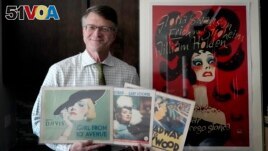 Dwight Cleveland, a major collector of movie posters and lobby cards, poses for a portrait with a three lobby card and movie poster Tuesday, Sept. 27, 2022, in Chicago. (AP Photo/Charles Rex Arbogast)