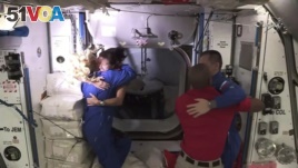 In this frame grab from NASA TV, astronaut Shannon Walker, second from left, is greeted by astronaut Kate Rubins, left, as she enters the International Space Station after arriving from the SpaceX Dragon capsule, early Tuesday, Nov. 17, 2020.