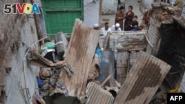 Pakistani residents look at a damaged house following an earthquake in Peshawar, on Oct. 26, 2015. AFP PHOTO / HASHAM AHMED