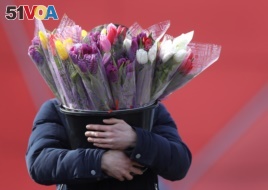 This man carries a bucket of tulips in Minsk, Belarus, March 7, 2019.