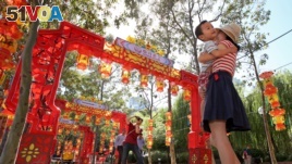 FILE - Pen Pu (center) and Chelsea Peng play with their three-year-old son Dore Peng at the Chinese Garden of Friendship in Sydney, Australia, 2015. (AP Photo/Rick Rycroft)