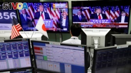 An employee of a foreign exchange trading company looks at monitors showing U.S. President elect Donald Trump speaking on TV news in Tokyo, Japan, Nov. 9, 2016.