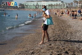 A man wearing a protective face mask carries a dog as he enjoys the sunny weather at Barceloneta beach, amid the coronavirus disease (COVID-19) outbreak, in Barcelona, Spain, May 21, 2020